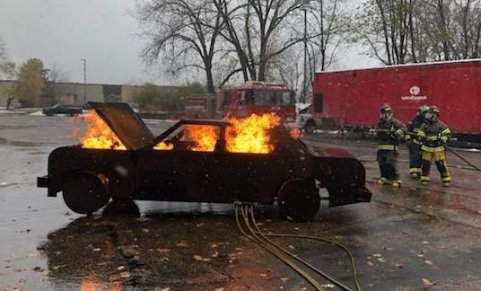 2名消防队员拿着水管试图扑灭汽车大火